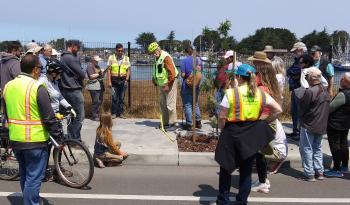 Dan Burden measuring sidewalk on Eureka waterfront as dozens watch. 